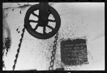 photographie Bastide. Roue du puits et plaque sur l'origine de la citerne Ph.1979.335.3  Photo