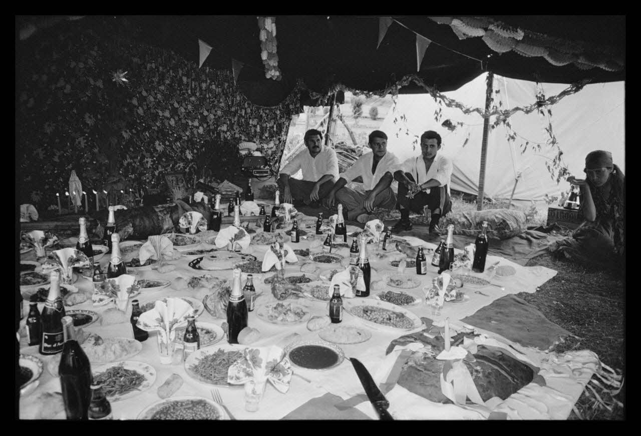 Philippe Lemaire De Marne photographie Roms, nomades "Kalderash". Fête traditionnelle "Prasmiko". Famille de "Papa" Gusman et Théodore Gusman, son frère dans un terrain loué à la sortie du village. Table de Théodore Midi-Pyrénées, France 1965/8/15 Ph.1966.68.75 Photo