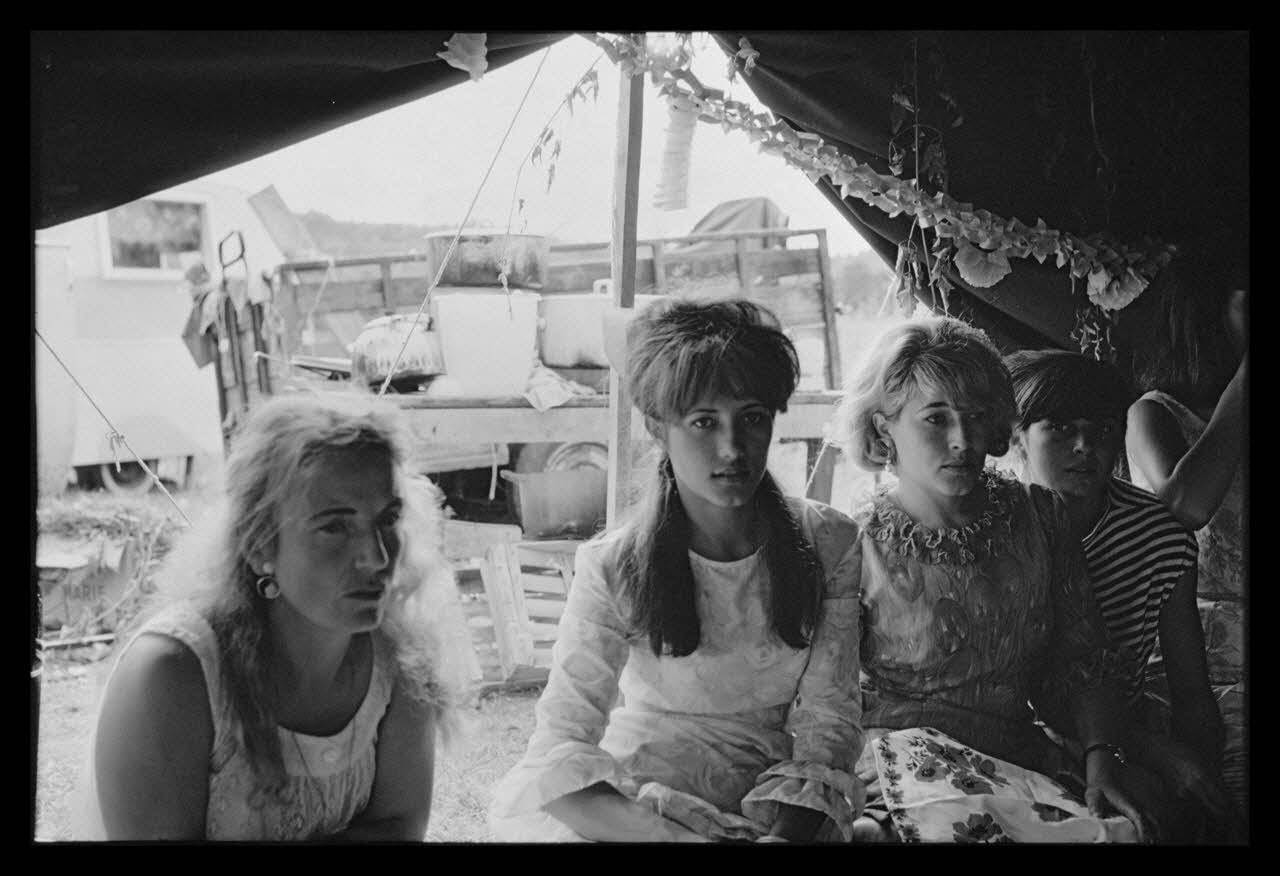 Philippe Lemaire De Marne photographie Roms, nomades "Kalderash". Fête traditionnelle "Prasmiko". Famille de "Papa" Gusman et Théodore Gusman, son frère dans un terrain loué à la sortie du village. Jeunes filles de Papa à table Midi-Pyrénées, France 1965/8/15 Ph.1966.68.79 Photo