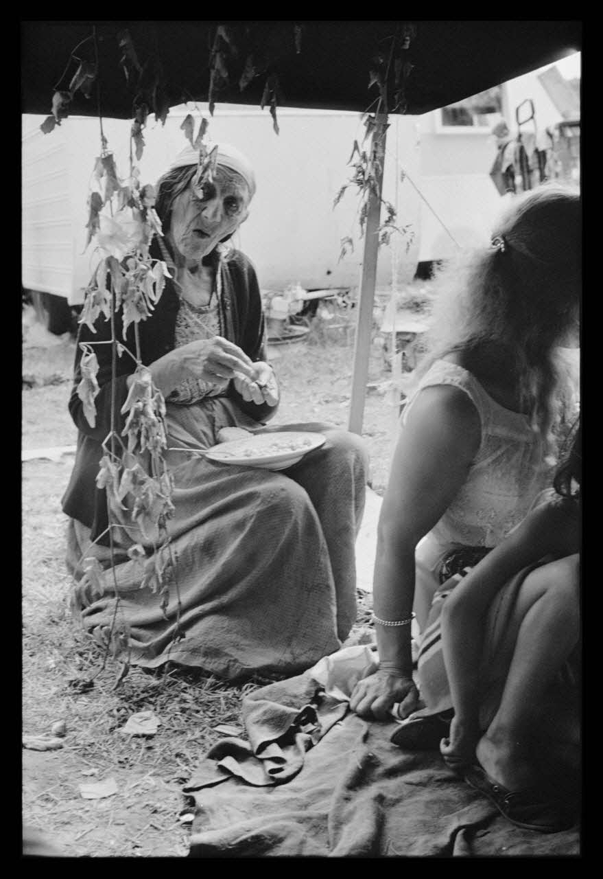Philippe Lemaire De Marne photographie Roms, nomades "Kalderash". Fête traditionnelle "Prasmiko". Famille de "Papa" Gusman et Théodore Gusman, son frère dans un terrain loué à la sortie du village. Vieille femme : "Milka" Gusman Midi-Pyrénées, France 1965/8/15 Ph.1966.68.81 Photo