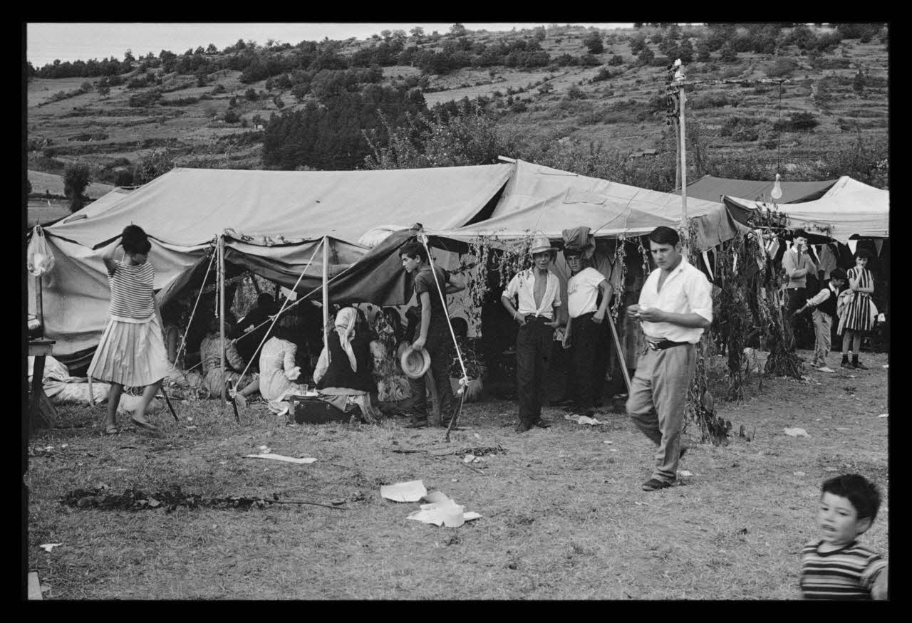 Philippe Lemaire De Marne photographie Roms, nomades "Kalderash". Fête traditionnelle "Prasmiko". Famille de "Papa" Gusman et Théodore Gusman, son frère dans un terrain loué à la sortie du village. Extérieur de la tente Midi-Pyrénées, France 1965/8/15 Ph.1966.68.84 Photo