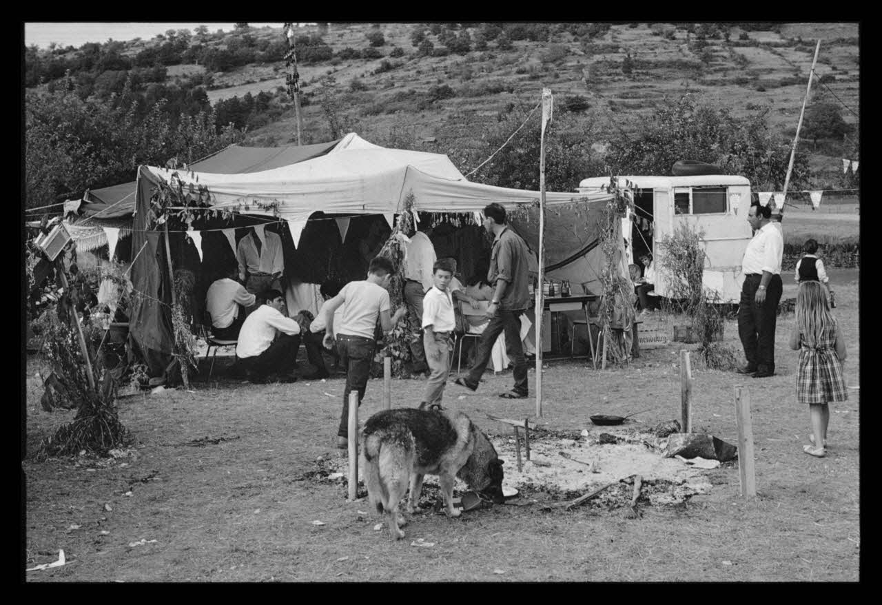 Philippe Lemaire De Marne photographie Roms, nomades "Kalderash". Fête traditionnelle "Prasmiko". Famille de "Papa" Gusman et Théodore Gusman, son frère dans un terrain loué à la sortie du village. Extérieur de la tente. Le feu Midi-Pyrénées, France 1965/8/15 Ph.1966.68.85 Photo