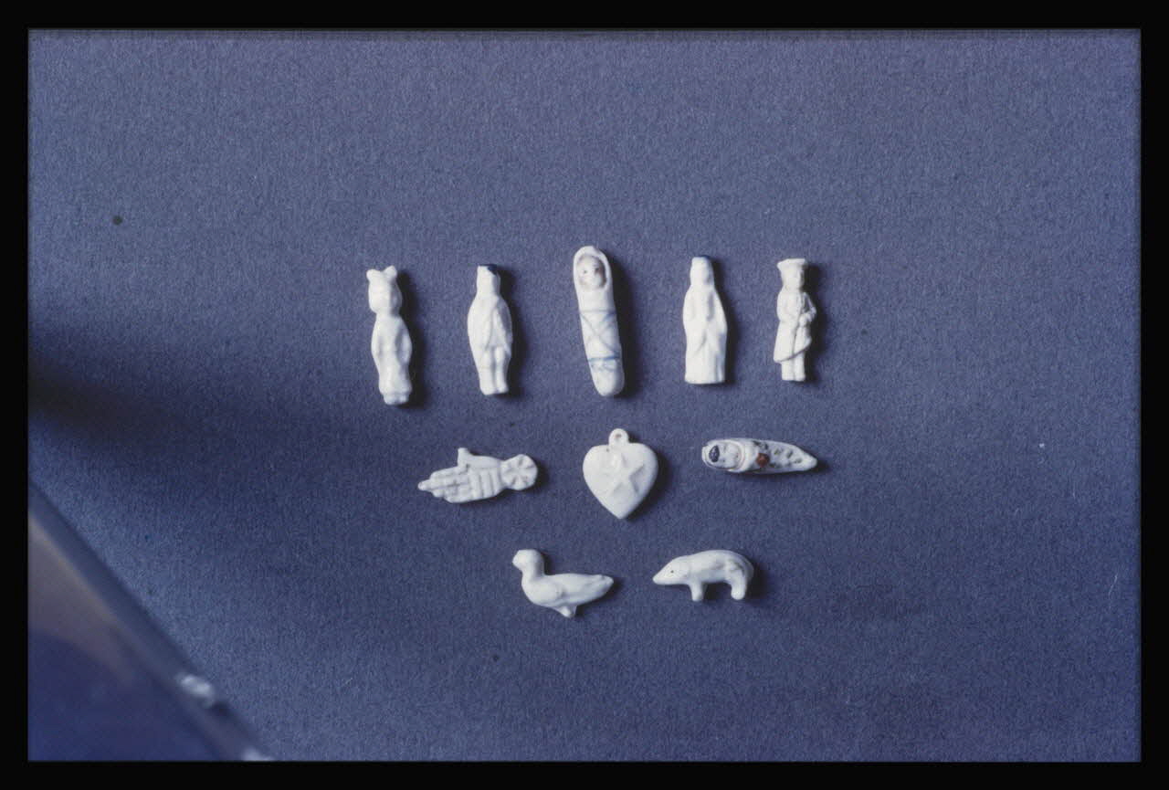 Bandy photographie Fèves pour gâteaux des rois en porcelaine blanche. Personnage debout, reine, bébé emmailloté, bébé nu, petite fille, sabot, cœur avec étoile à cinq branches, main de Fatima, animal (belette ?), canard Ile-de-France, France 1959/6/1 Ph.1959.102.35 Photo