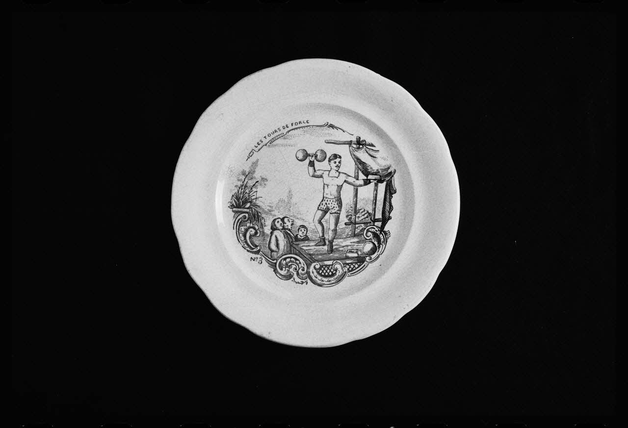 photographie Assiette plate en faïence fine du 19è siècle avec un décor représentant un haltérophile Ph.1984.1.274 Photo