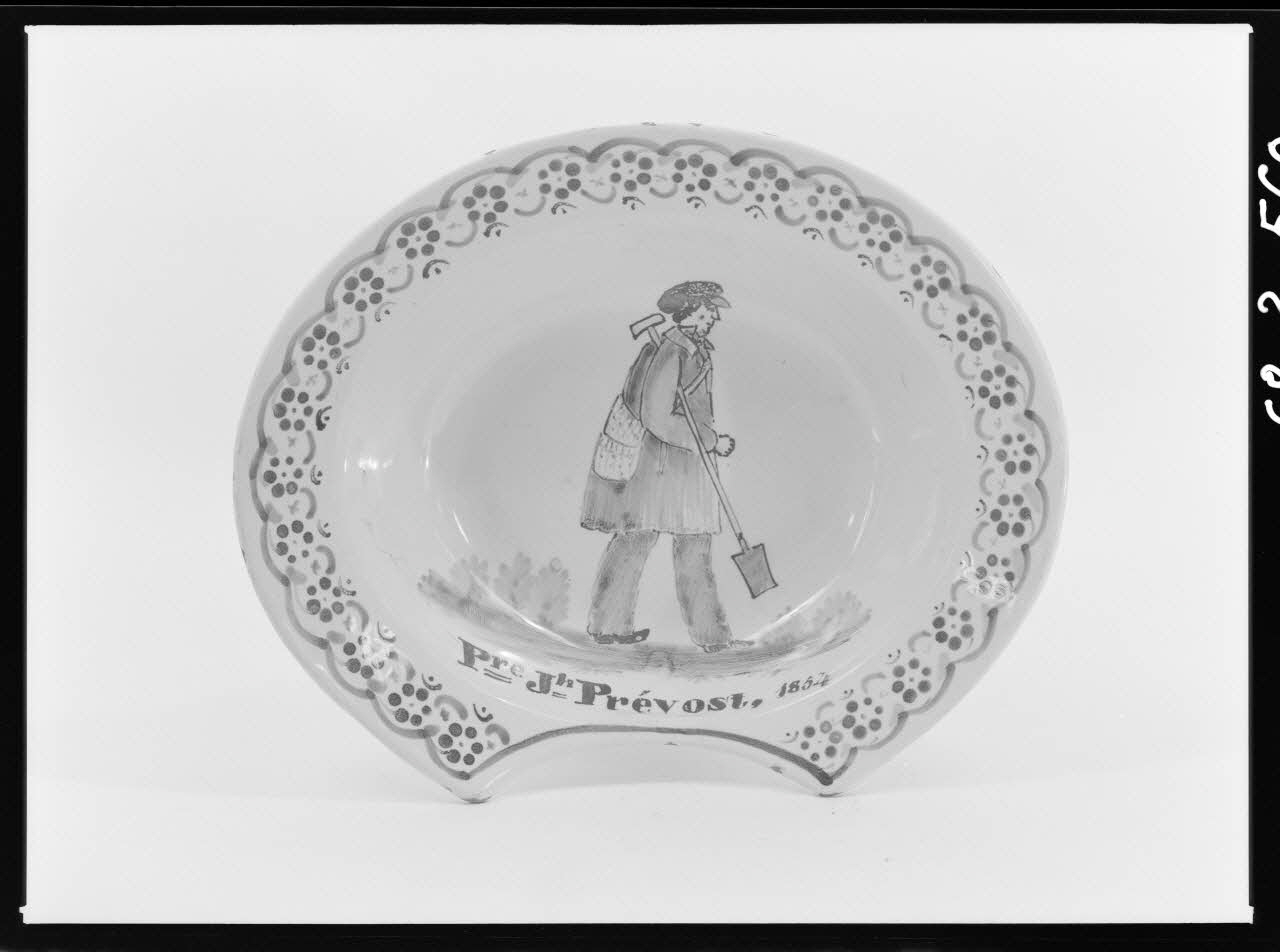 Alain Guey photographie Plat à barbe en faïence polychrome. Décoré au fond d'un homme avec une casquette tenant une bêche, et de l'inscription: "Auguste Prévost. 1854" Ile-de-France, France 1968/3/1 Ph.1968.3.560 Photo