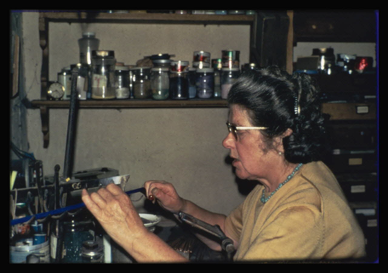 Anonyme photographie Transformation et utilisation du verre. Emailleuse en train de faire des perles artificielles. Pour faire la perle avec une baguette de cuivre le verre est flamme et la perle se détache Ile-de-France, France 1967 Ph.1984.26.1 Photo