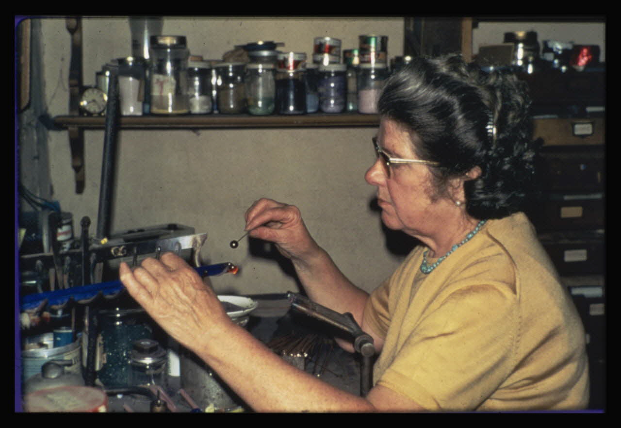 Anonyme photographie Transformation et utilisation du verre. Emailleuse en train de faire des perles artificielles. La perle est prête à être émaillée Ile-de-France, France 1967 Ph.1984.26.3 Photo