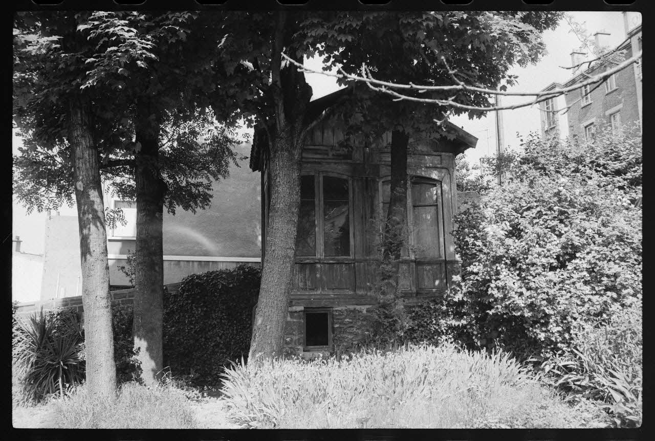photographie Maison construite en bois ayant servi aux bureaux et à la vente des billets de la Société Parisienne des bus. Transportée et posée sur une infrastructure en pierre afin de servir de cabane de week-end pour la famille Moreau dans leur jardin à Issy-les-Moulineaux Ph.1977.86.1 Photo