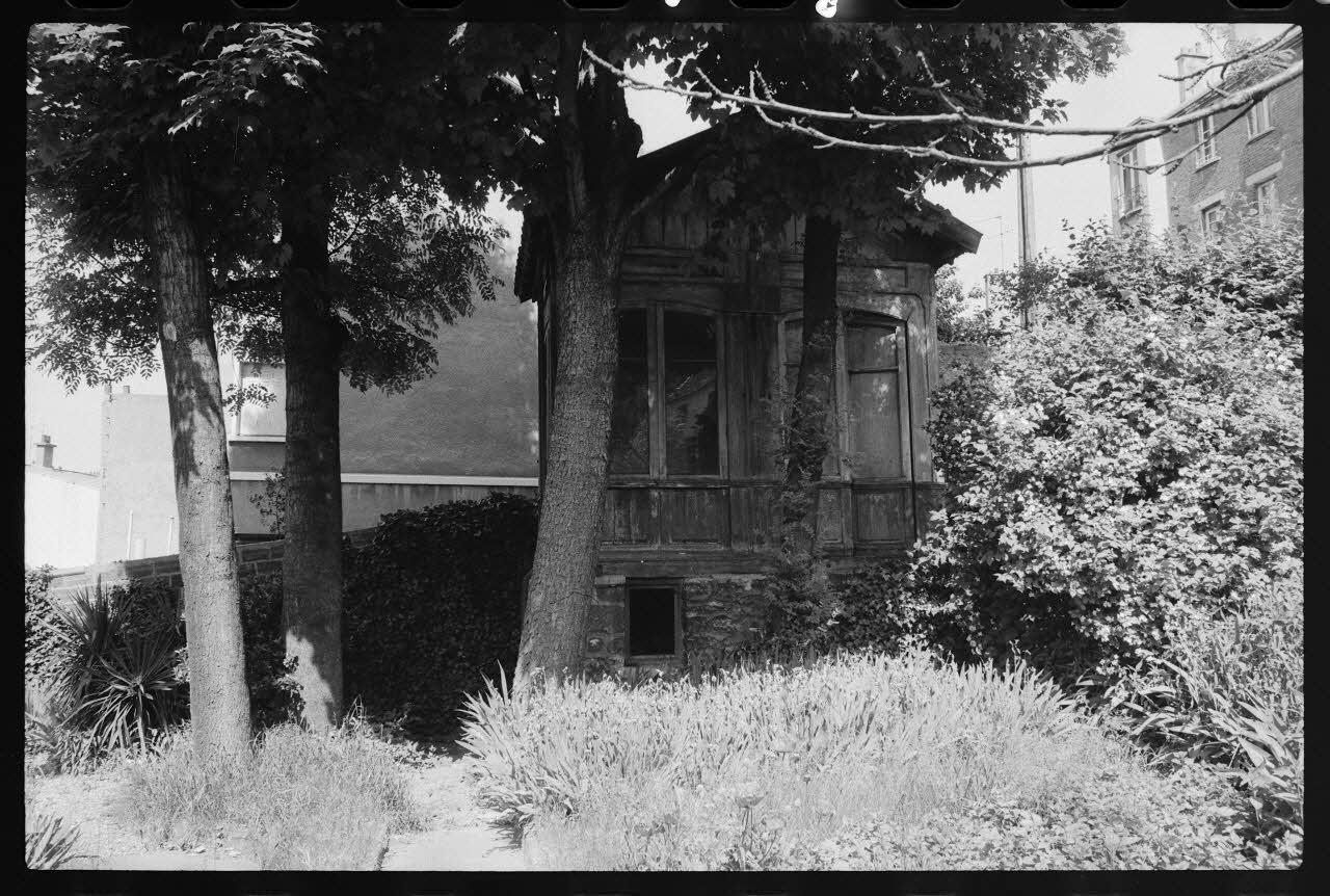 photographie Maison construite en bois ayant servi aux bureaux et à la vente des billets de la Société Parisienne des bus. Transportée et posée sur une infrastructure en pierre afin de servir de cabane de week-end pour la famille Moreau dans leur jardin à Issy-les-Moulineaux Ph.1977.86.2 Photo