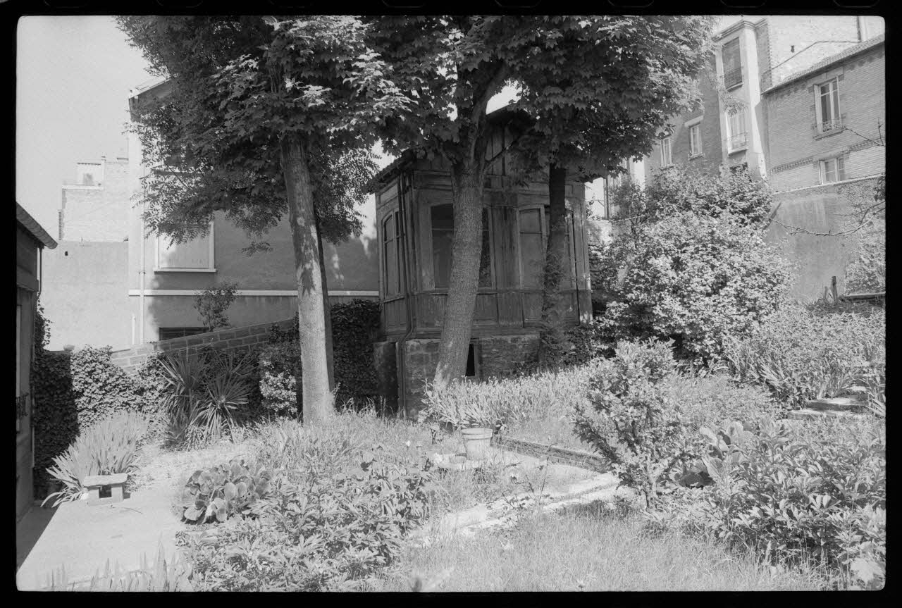 photographie Maison construite en bois ayant servi aux bureaux et à la vente des billets de la Société Parisienne des bus. Transportée et posée sur une infrastructure en pierre afin de servir de cabane de week-end pour la famille Moreau dans leur jardin à Issy-les-Moulineaux Ph.1977.86.3 Photo
