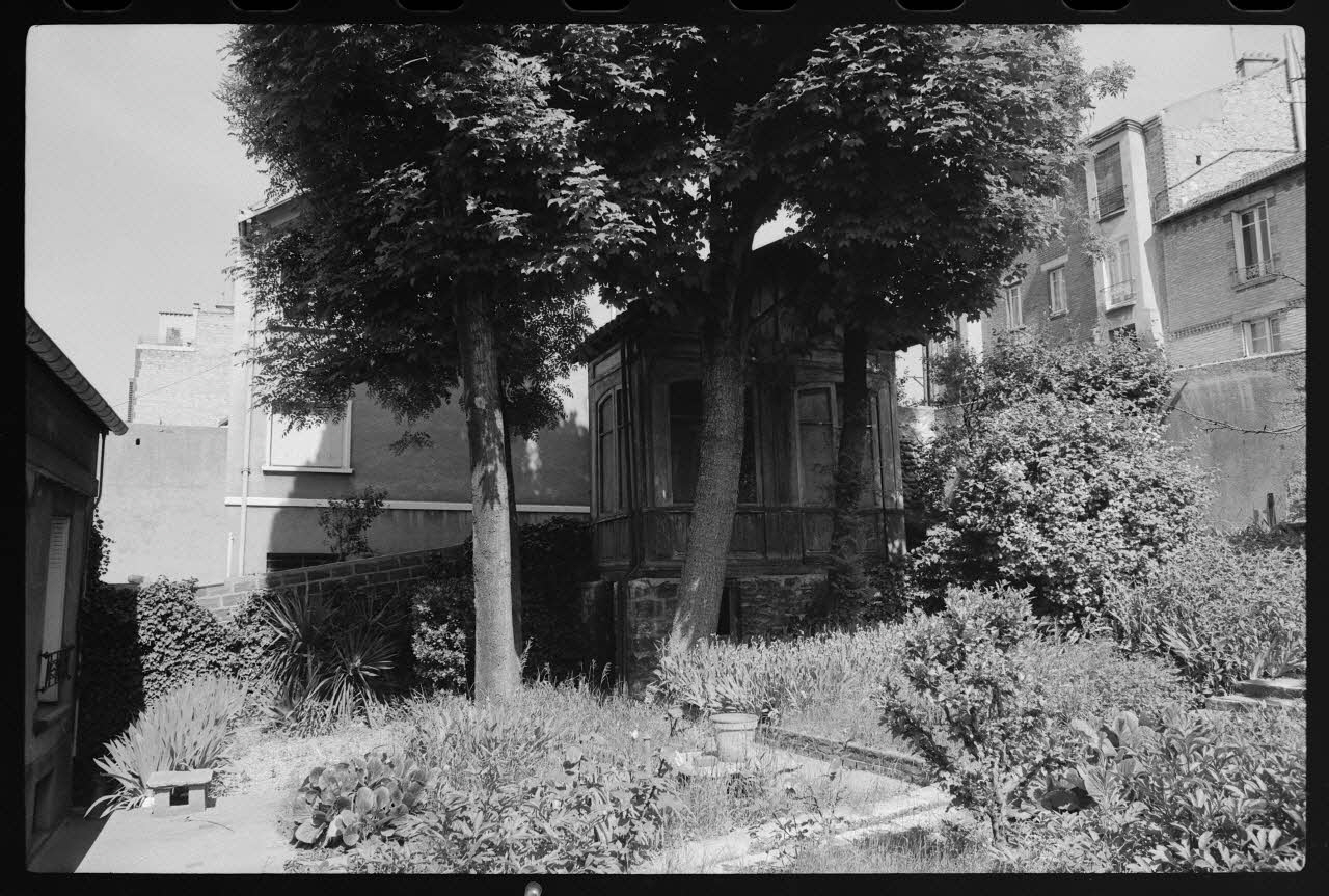 photographie Maison construite en bois ayant servi aux bureaux et à la vente des billets de la Société Parisienne des bus. Transportée et posée sur une infrastructure en pierre afin de servir de cabane de week-end pour la famille Moreau dans leur jardin à Issy-les-Moulineaux Ph.1977.86.4 Photo