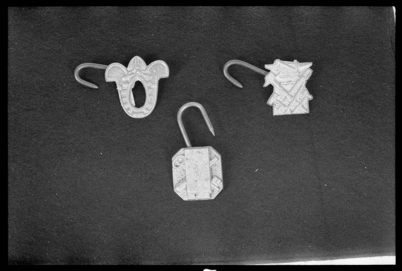 Alain Guey photographie Crochet de tablier de bourrelier fixés dans une plaque découpée représentant un collier. Crochet de tablier de forgeron fixés dans une plaque découpée représentant une enclume. Crochet de tablier de e serrure Ile-de-France, France 1974 Ph.1974.63.63 Photo