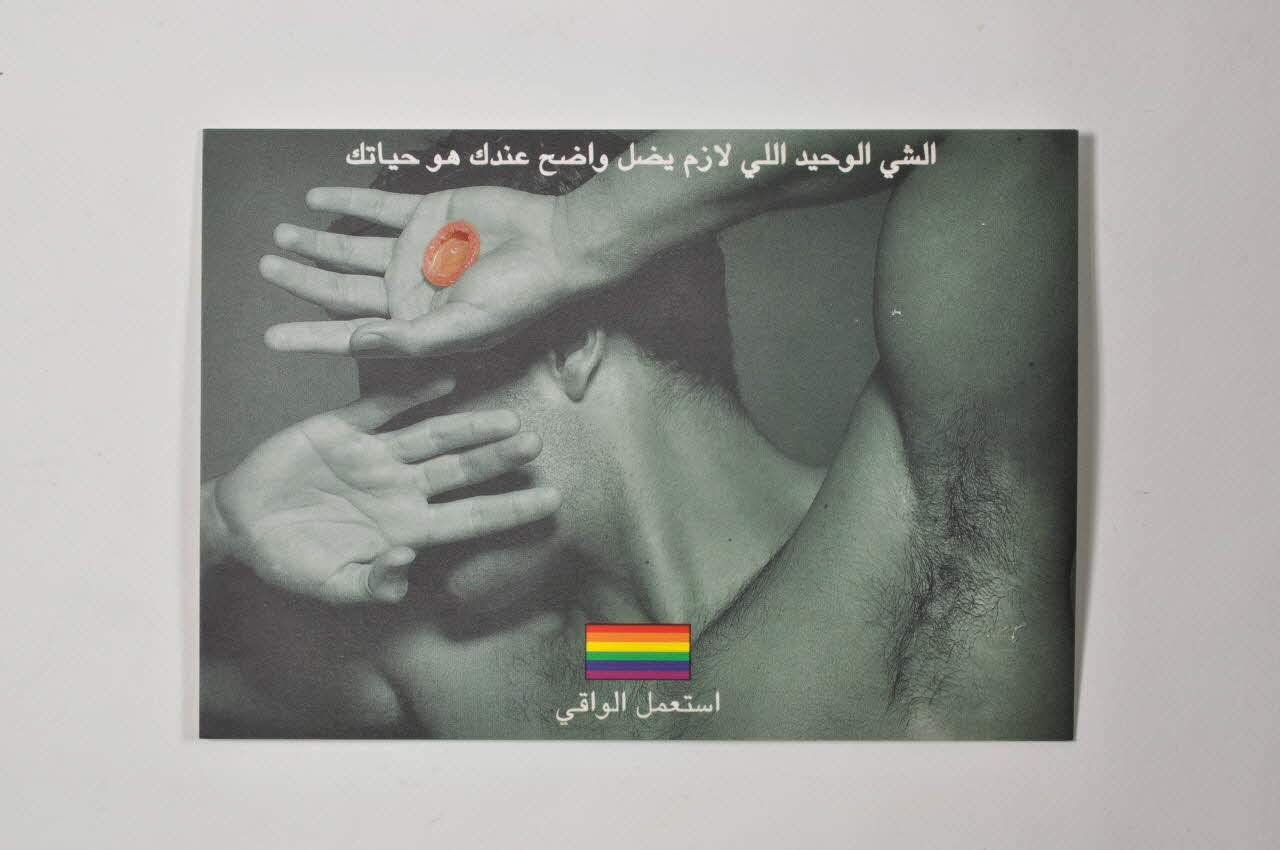 carte postale homme se cachant le visage tenant un préservatif, drapeau arc en ciel, préservatif collé au verso 2005.119.47 Photo Mucem