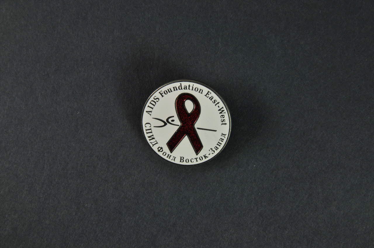 Aids Foundation East-West (AFEW) Pin's ruban rouge Pin's ruban rouge et nom de l'association Fédération de Russie 2004 2004.239.20.1-2 Photo Mucem