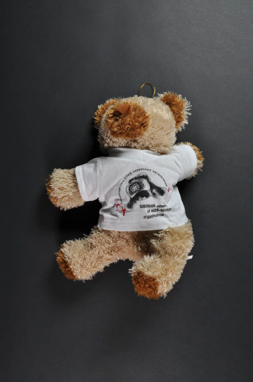 Siberian Network Of Aids - Service Organizations peluche Ours en peluche avec ruban rouge portant tee-shirt de Siberian Network of AIDS-Service organizations Russie 2004 2004.247.1 Photo Mucem