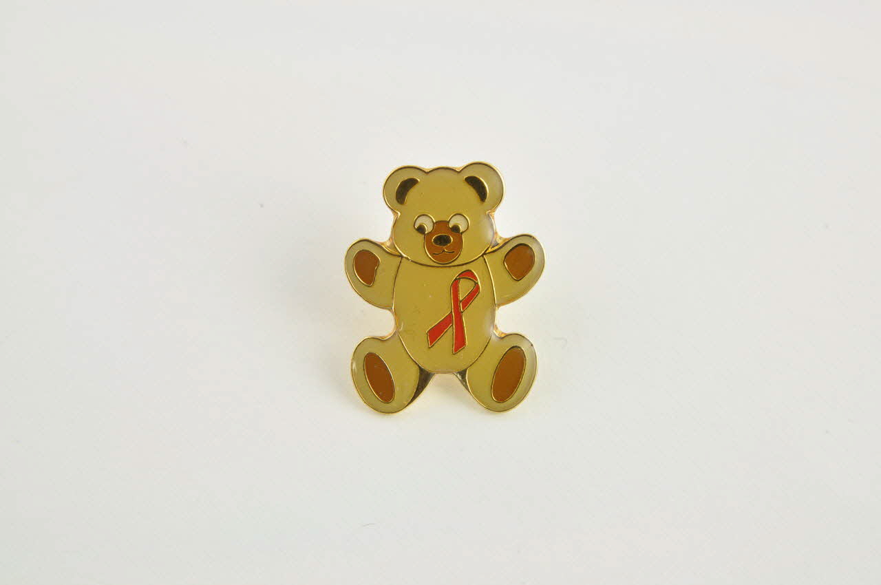 pin's Pin's nounours ruban rouge brun clair Belgique 2004 2004.248.1.1-2 Photo Mucem