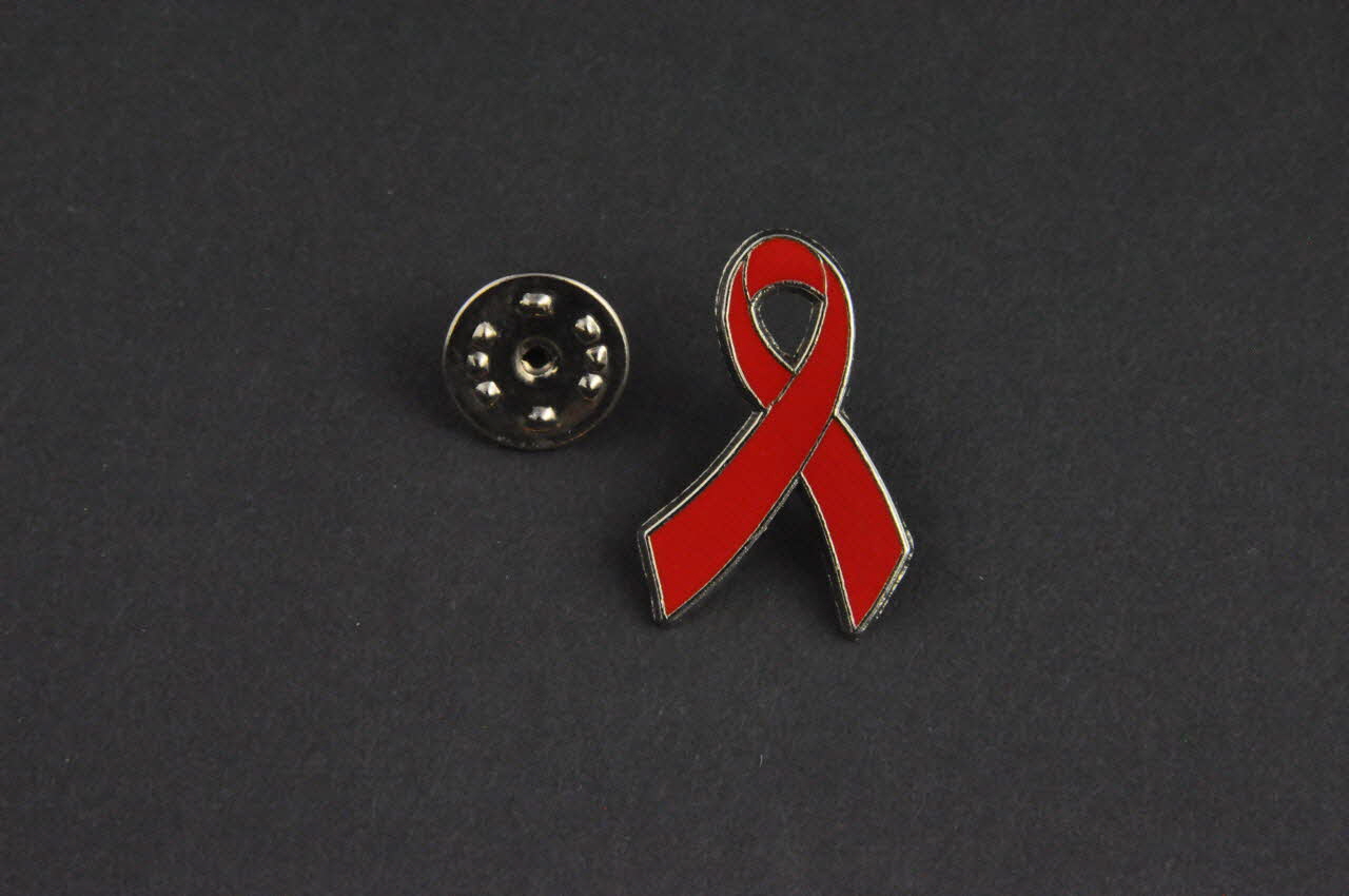 Comité 1er Décembre Pin's ruban rouge Pin's Ruban rouge surligné par une ligne argentée Espagne 2002 2003.93.28.1.1-2 Photo Mucem