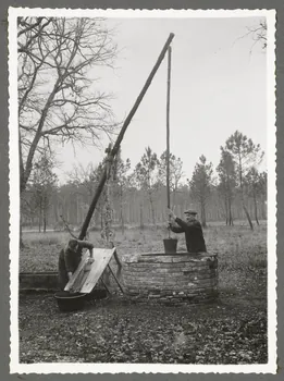 Emile Vignes photographie Puits à balancier. Homme puisant de l'eau et femme lavant le linge  avec une selle à laver et un baquet de bois Aquitaine, France 1941 Ph.1941.58.28 Photo