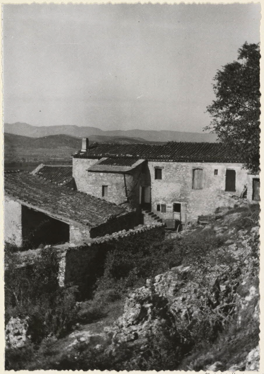 Adrienne Durand-Tullou photographie Le mas de Revel. La terrasse est remplacée par une pièce en avancement dite "lou revelin". Toiture mixte en lauzes et tuiles. Entrée de grange couverte au premier plan Languedoc-Roussillon, France 1955 Ph.1955.45.8 Photo