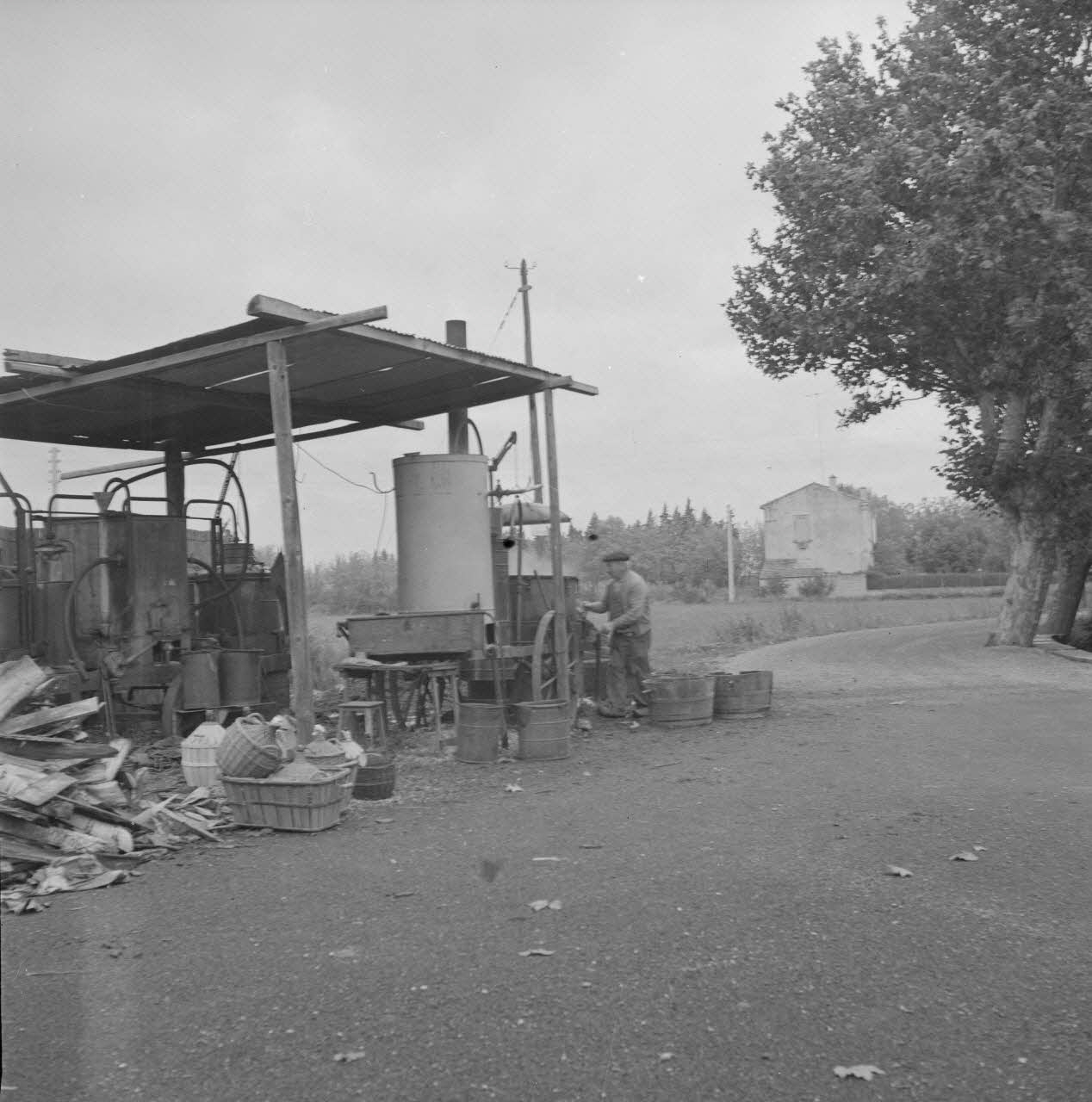M. Richet photographie L'alambic de Monsieur Jean Caban, distillateur au travail. Il a soulevé le couvercle de la cuve ayant contenu le marc qui vient de bouillir Provence-Alpes-Côte d'Azur, France 1962/10/12 Ph.1963.31.15 Photo
