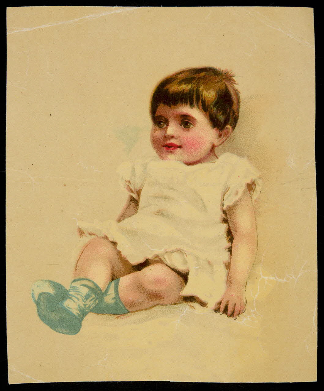 carte réclame Enfant en robe blanche et chaussons bleus couché sur le dos 1998.77.318.1 Photo