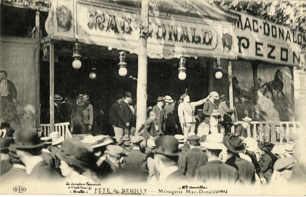Ernest-Louis-Désiré Le Deley Fête de Neuilly. Ménagerie Mac Donald.1911. [de gauche à droite :] Le dompteur Fernando et l'ours brun Nenette, le piston M. Bruneau, Mlle Annietta. Hauts-de-Seine, Paris (75) 1911 Sou.5.110.2 Photo