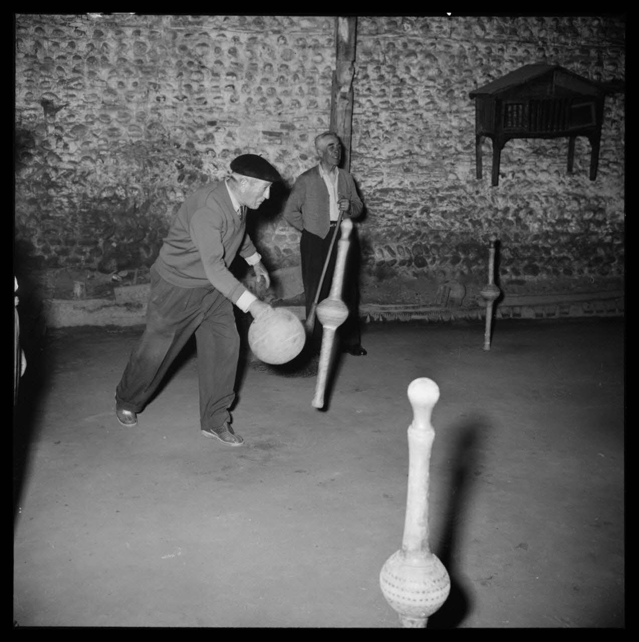 R. Lapeyre photographie Café Darré. Jeu de quilles de neuf. Le joueur tient toujours la boule, elle vient d'entrer en contact avec la quille qu'elle a projeté Midi-Pyrénées, France 1960/5/12 Ph.1960.68.29 Photo Mucem / Lapeyre, R.