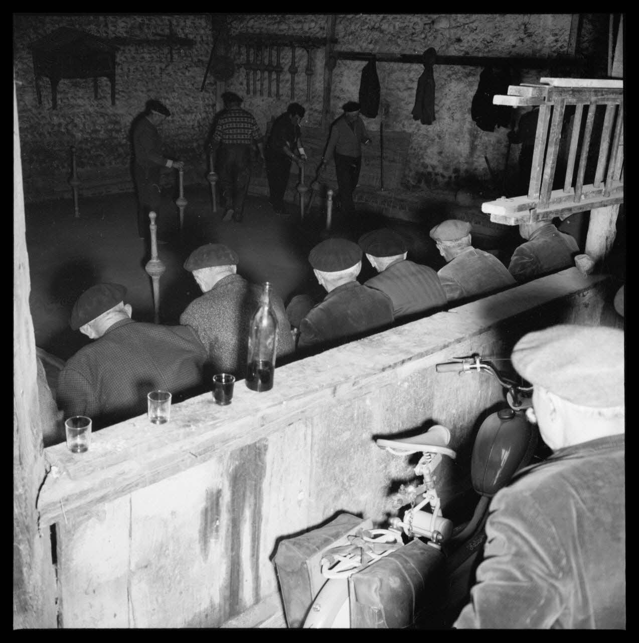 R. Lapeyre photographie Café Darré, rue Lamartine. Jeu de quilles de neuf. Spectateurs assis, avec des verres et des litres de vin rouge. Au fond, le quillier Midi-Pyrénées, France 1960/5/12 Ph.1960.68.43 Photo Mucem / Lapeyre, R.
